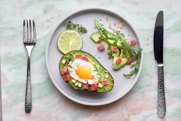 Baked Avocado boat with ham cubes, quail egg and cheese served with green rucola salad