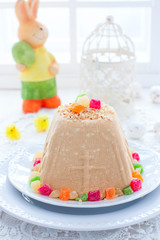 Traditional curd Easter with condensed milk, nuts and candied fruits on a white plate in a festive light decor, selective focus