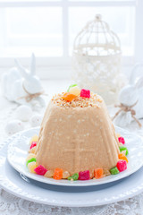 Traditional curd Easter with condensed milk, nuts and candied fruits on a white plate in a festive light decor, selective focus