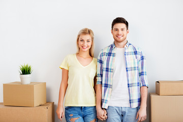 Fototapeta na wymiar mortgage, people and real estate concept - happy couple with boxes moving to new home