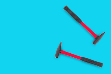 Pair of metal hammers with red and black rubber handle on blue background with copy space for your text