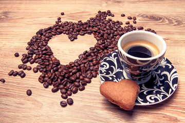 Heart make whit coffee beans and cup whit espresso and sweet heart cookie on wood table background. 