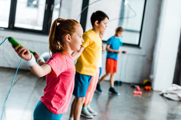 Preteen kids training with skipping ropes in gym