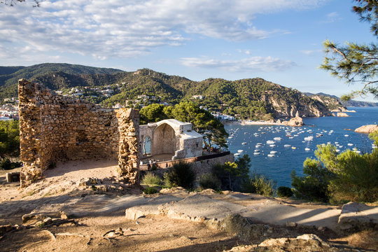 Ruins of the Roman village of Els Ametllers. View from the castle hill towards the beach. Castle tower and fragment of walls. Tossa de Mar town on the Costa Brava, Spain. Ruins of the old town of Vila