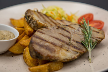 A dish of fried pieces of meat with potatoes, tomatoes and specialties on a light plate