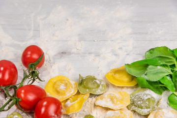 Naklejka na ściany i meble Homemade fresh Italian ravioli pasta on white wood table with flour, basil, tomatoes,background,top view.
