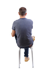 Back view of a man sitting on a chair.