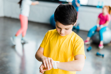 Boy in yellow t-shirt looking at smartwatch