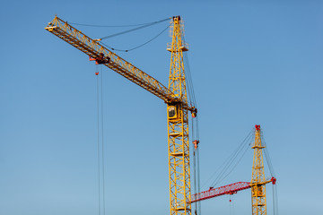 Fototapeta na wymiar The yellow crane in the daylight. Construction technology. Modern construction crane for lifting building materials