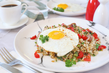  Spicy roast rice with red cherry tomatoes, sausages, fried eggs and cup of coffee for breakfast