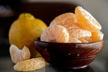 tangerines or orange fruit slices in a bowl on wooden table