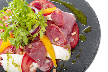 Fresh italian caprese salad with mozzarella and tomatoes on dark plate