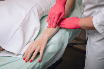 Beautician removes hair from a woman's hand. Sugaring. Hair removal with a special sugar paste has many advantages over wax depilation. Close up.