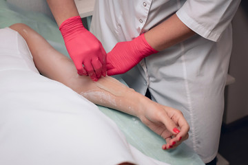 Obraz premium Beautician removes hair from a woman's hand. Sugaring. Hair removal with a special sugar paste has many advantages over wax depilation..