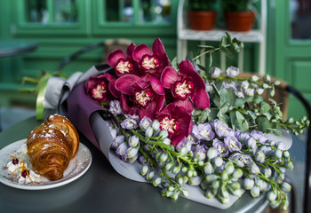 Wedding bouquet with dessert lying on wooden table in bride room.
