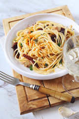 Italian food. Spaghetti with dried tomatoes, grilled chicken and glass of white wine