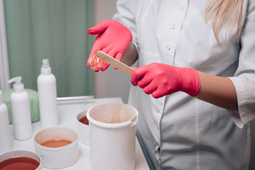 Sugaring master in pink gloves holds Wand with sugaring wax. Depilation and beauty concept..