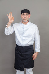 Fototapeta premium Elderly chef on grey background, isolated, concept