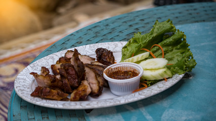 Roasted pork cut into sheen and water in a white plate on the table