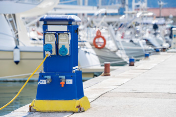 Yacht dock on a bright sunny day, view from below. White yachts and motor boats stand in a row along the pier