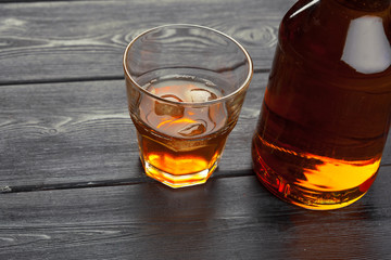 bottle and glass of whiskey on a wooden background