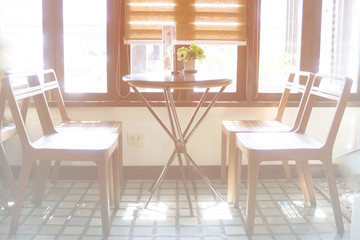 A set of chairs in a coffee shop with light shining through the