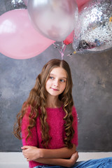 Girl with pink, grey balloons on grey background. Beautiful happy girl. Joyful model posing, celebrating Valentine's day.