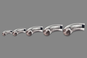 Row of chrome corrugated elbows of pipes for air, water, oil or gas on gray background
