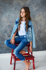 Girl model sitting on a red chair, gray background
