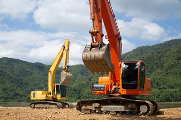 Excavator in construction equipment site on river and mountain and sky background