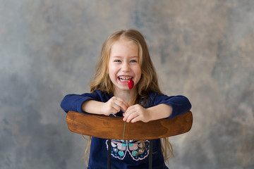 Little girl holding two little red hearts. The concept of Valentine's Day. gray background.