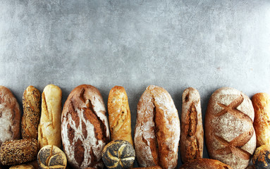Assortment of baked bread and bread rolls on stone table background