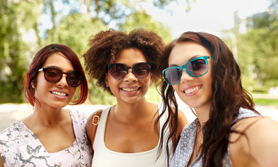 female friendship, people and leisure - happy young women in sunglasses at summer park