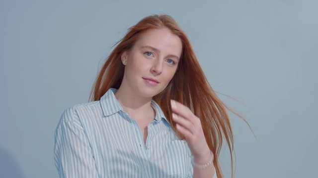gingerhead red hair, ginger hair model with blue big eyes in studio with blowing hair in slow motion from 60fps. Beauty straight shiny hair blowing,