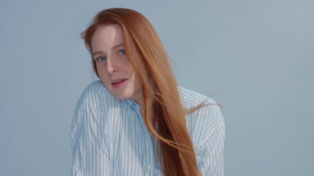 gingerhead red hair, ginger hair model with blue big eyes in studio with blowing hair in slow motion from 60fps. Beauty straight shiny hair blowing,