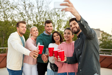 leisure and people concept - happy friends with non alcoholic drinks taking selfie by smartphone at...
