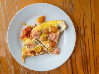 Top view on plate with omelette cooked with  cherries tomato and pieces of sausage
