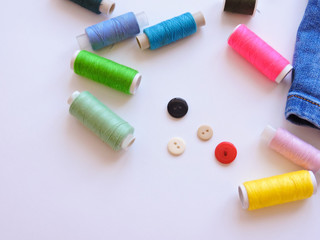 Fototapeta na wymiar Colorful treads for sewing.Sewing supplies and accessories for needlework- scissors, needles, yellow measuring tape, thread on a table. Close up group of Multicolored spools of thread use to sewing. 