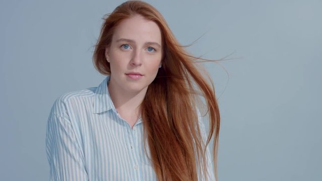 gingerhead red hair, ginger hair model with blue big eyes in studio with blowing hair in slow motion from 60fps. Beauty straight shiny hair blowing,