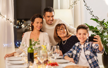 celebration, holidays and people concept - happy family having dinner party at home and taking selfie by smartphone