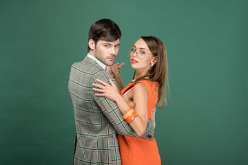 beautiful couple in vintage clothes dancing and looking at camera isolated on green