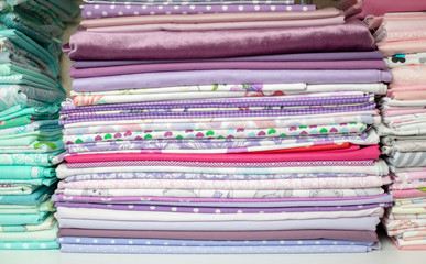 lots of bundles of different verities of new fabric in many color collections kept on the shelf of a local store in Asia