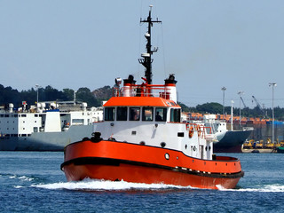 Red Tugboat underway in harbour boundries to towing assistance operation.