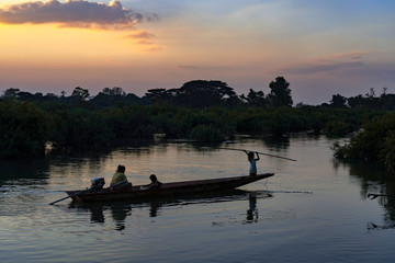 Laotian woman with two children heading home on the boat on Mekong River, at sunset , 4000 islands, Don Det, Laos