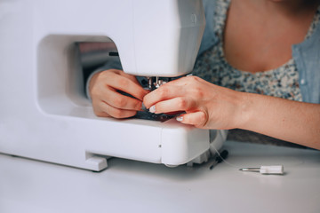  young woman seamstress sitting and sews on sewing machine. Tailor making a garment in her workplace. Hobby as a small business concept. Close up photo