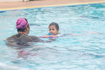 Boy learning to swim with coach.