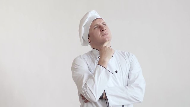 The chef is the man in the hat standing to the waist in a bright room, holding the hand of a person and something is seriously thinking