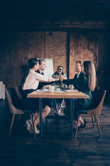 Close up vertical view photo glad employee business people he him his she her partners sit table office together arms gathered together team spirits building achievement dressed suits formal wear