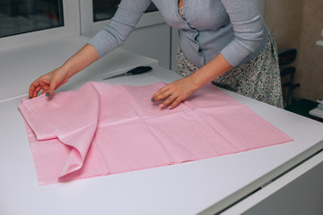 Close up. hands woman Tailor working cutting a roll of fabric on which she has marked out the pattern of the garment