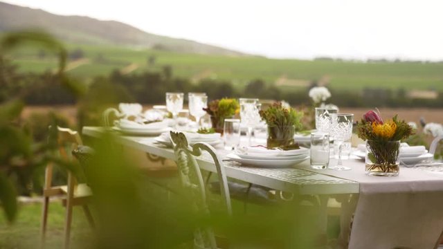 Table setting for a party with crockery and flowers. Beautiful table place setting for a dinner party outdoors.